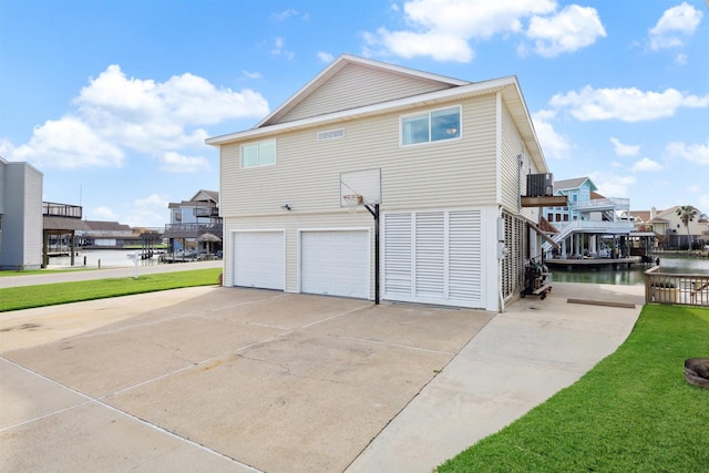 view of home's exterior featuring a lawn, a garage, a water view, and cooling unit