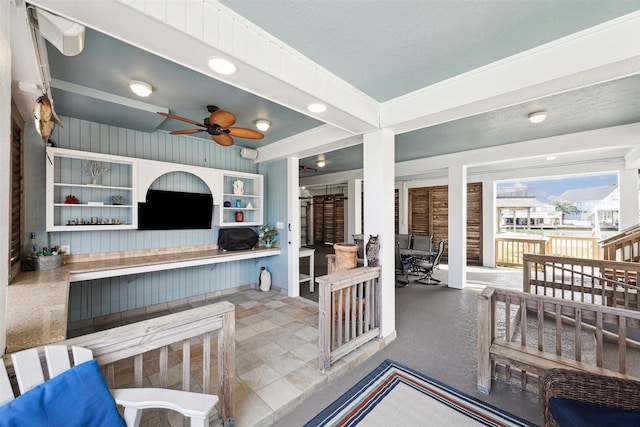 living room featuring ceiling fan and wood walls