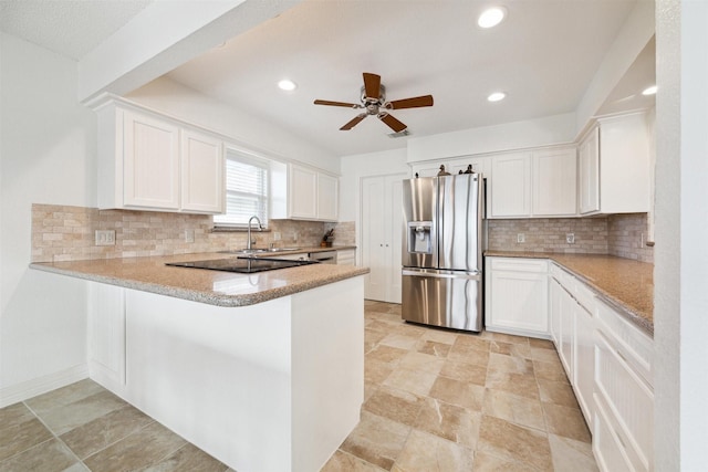 kitchen featuring backsplash, kitchen peninsula, stainless steel fridge, and white cabinets