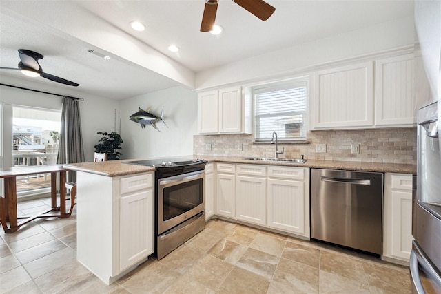 kitchen with kitchen peninsula, appliances with stainless steel finishes, backsplash, sink, and white cabinetry