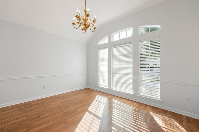 empty room featuring hardwood / wood-style floors, lofted ceiling, crown molding, and an inviting chandelier