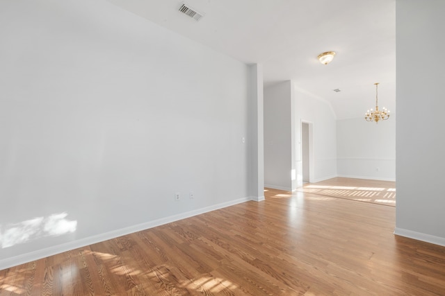 empty room featuring light wood-type flooring and a chandelier