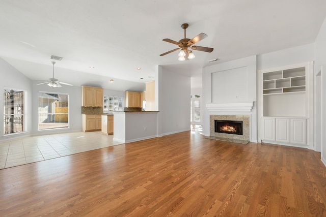 unfurnished living room with plenty of natural light, ceiling fan, vaulted ceiling, and light hardwood / wood-style flooring