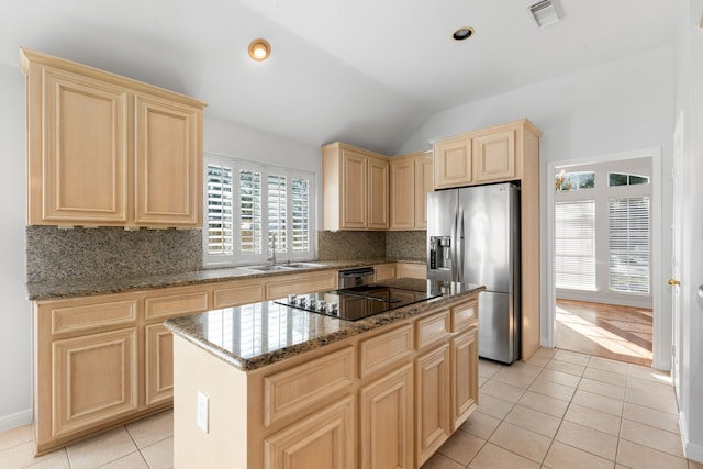 kitchen with a center island, stone counters, sink, vaulted ceiling, and appliances with stainless steel finishes