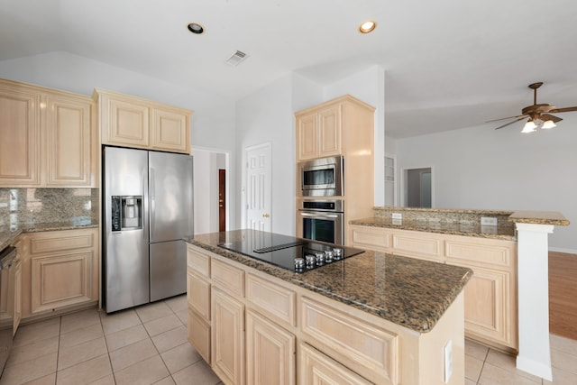 kitchen featuring a center island, ceiling fan, decorative backsplash, dark stone countertops, and appliances with stainless steel finishes