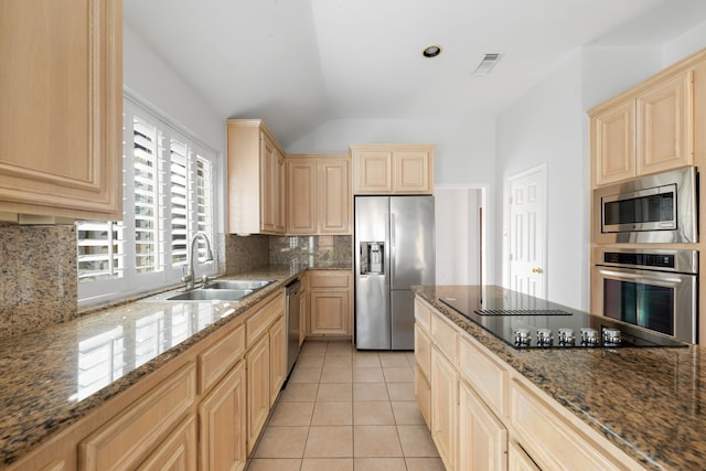 kitchen featuring sink, dark stone counters, decorative backsplash, light tile patterned flooring, and appliances with stainless steel finishes