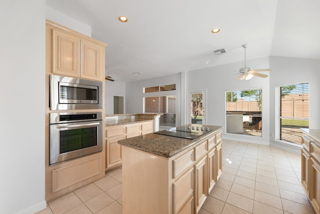 kitchen featuring a center island, dark stone counters, vaulted ceiling, appliances with stainless steel finishes, and light tile patterned flooring