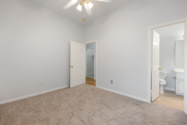 unfurnished bedroom with ceiling fan, ensuite bathroom, and light colored carpet