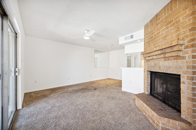 unfurnished living room featuring carpet, ceiling fan, a textured ceiling, and a brick fireplace