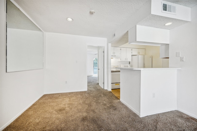 interior space with white appliances, white cabinets, a textured ceiling, light colored carpet, and kitchen peninsula