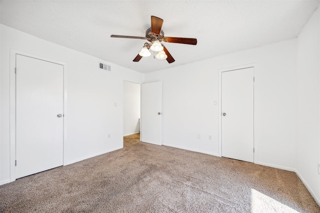 unfurnished bedroom with carpet, ceiling fan, and a textured ceiling