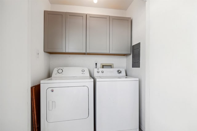 clothes washing area featuring electric panel, cabinets, and washer and dryer