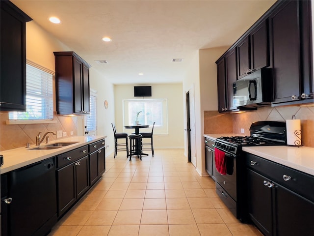 kitchen with light tile patterned flooring, decorative backsplash, sink, and black appliances