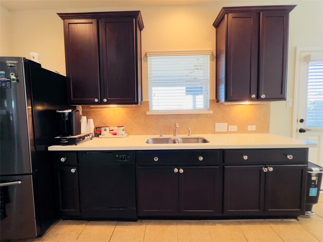 kitchen with decorative backsplash, light tile patterned floors, stainless steel refrigerator, and sink