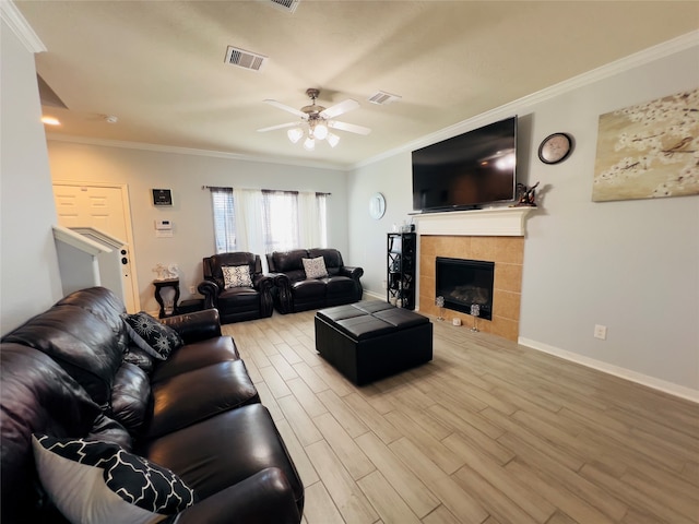 living room with light hardwood / wood-style floors, ceiling fan, ornamental molding, and a tiled fireplace