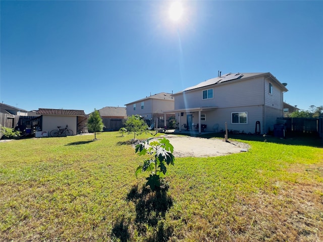 back of property with solar panels, a yard, and a patio