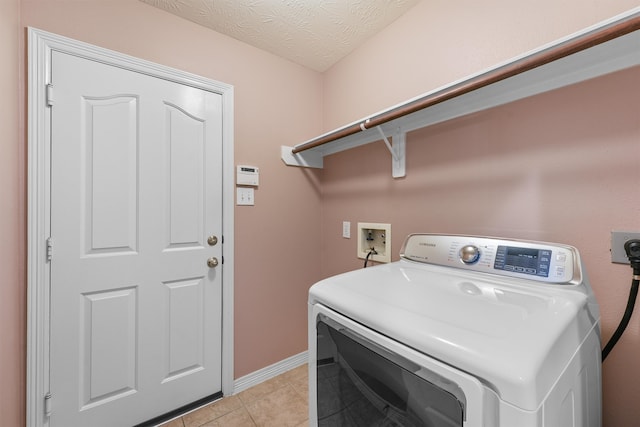 washroom with light tile patterned flooring, washer / dryer, and a textured ceiling