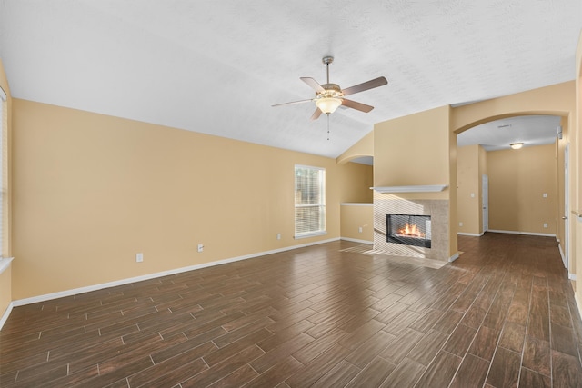 unfurnished living room with a textured ceiling, ceiling fan, dark wood-type flooring, and vaulted ceiling