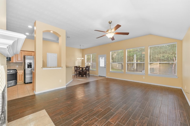 unfurnished living room with ceiling fan with notable chandelier, hardwood / wood-style flooring, and lofted ceiling