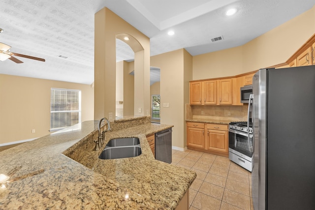 kitchen featuring a textured ceiling, stainless steel appliances, light stone counters, and sink