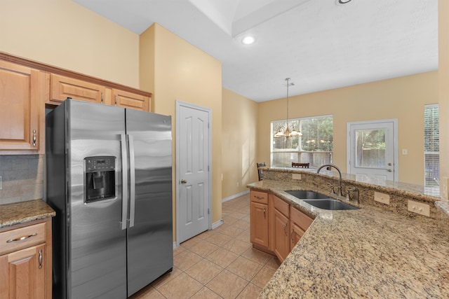 kitchen featuring decorative backsplash, light stone counters, sink, a chandelier, and stainless steel fridge with ice dispenser