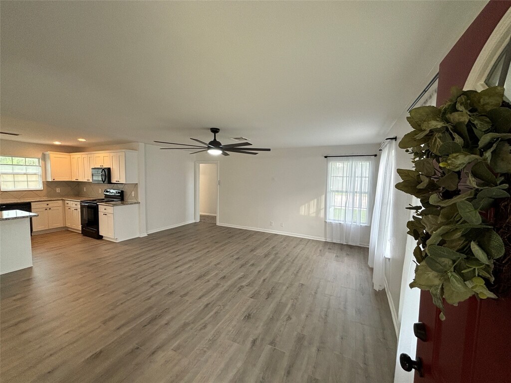 unfurnished living room with ceiling fan and light wood-type flooring