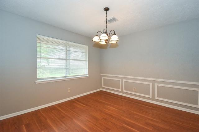 empty room featuring a chandelier and hardwood / wood-style floors