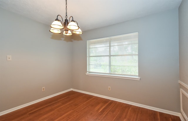 unfurnished room with wood-type flooring and a notable chandelier