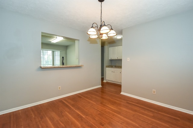 spare room featuring a chandelier, a textured ceiling, and hardwood / wood-style flooring