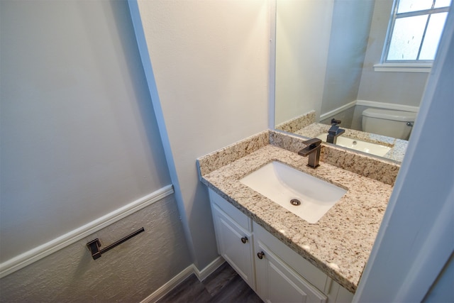 bathroom with hardwood / wood-style floors, vanity, and toilet