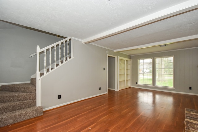 unfurnished living room with beamed ceiling, hardwood / wood-style floors, a textured ceiling, and wooden walls