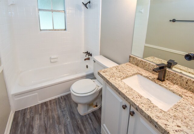 full bathroom featuring tiled shower / bath combo, toilet, wood-type flooring, and vanity