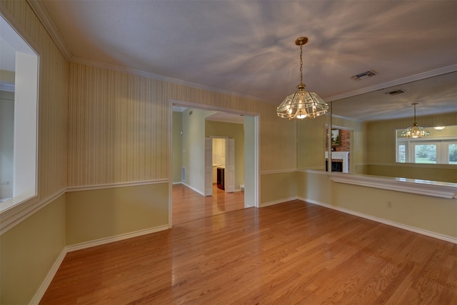 spare room featuring ornamental molding, light hardwood / wood-style flooring, and a notable chandelier