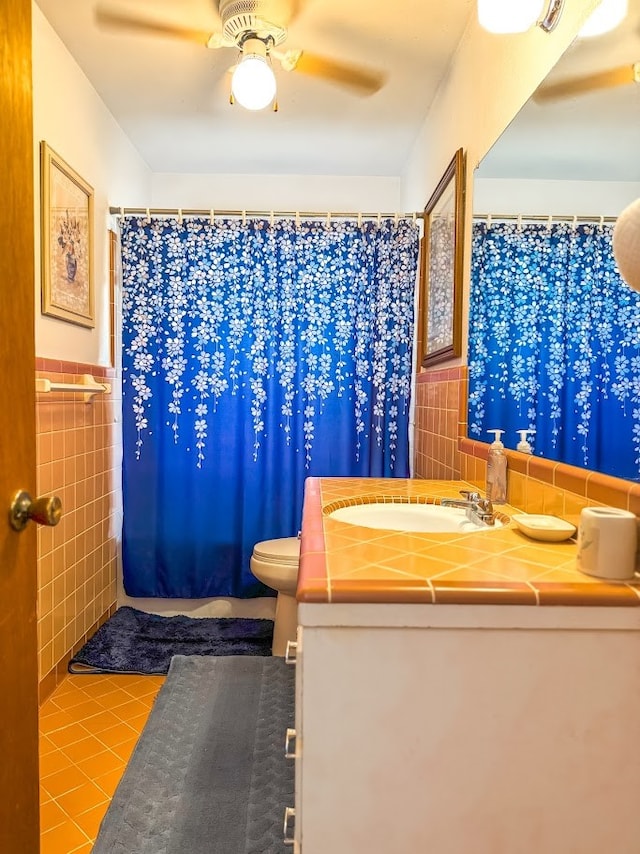 bathroom featuring vanity, tile patterned flooring, toilet, tile walls, and curtained shower