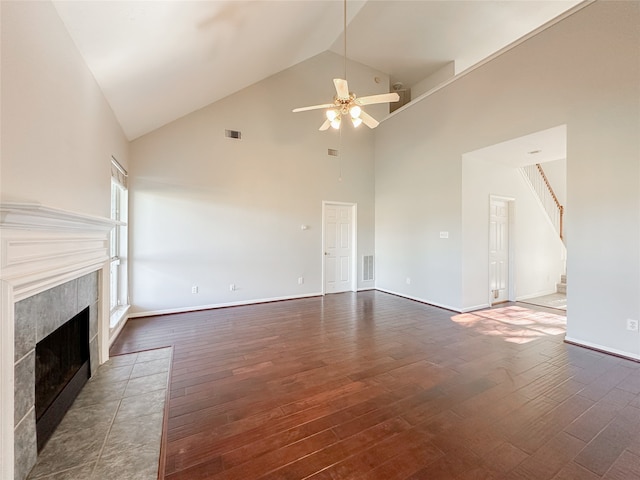 unfurnished living room with dark hardwood / wood-style floors, ceiling fan, a tile fireplace, and high vaulted ceiling