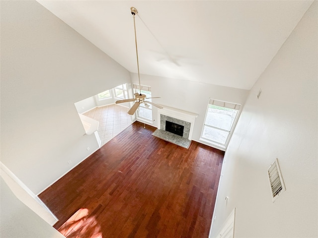 unfurnished living room with dark hardwood / wood-style floors, ceiling fan, a tile fireplace, and high vaulted ceiling