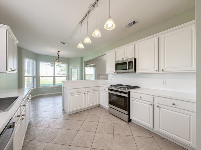 kitchen with white cabinets, light tile patterned flooring, decorative light fixtures, and appliances with stainless steel finishes