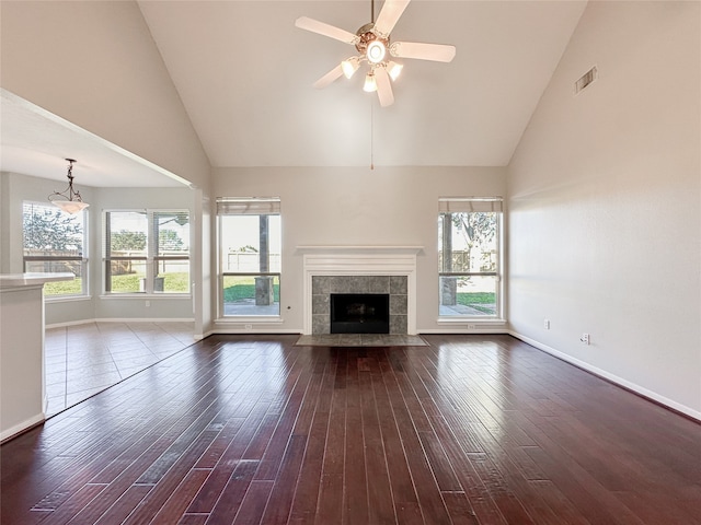 unfurnished living room featuring a tiled fireplace, ceiling fan, high vaulted ceiling, and dark hardwood / wood-style floors