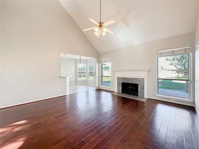 unfurnished living room with ceiling fan with notable chandelier, a fireplace, high vaulted ceiling, and dark hardwood / wood-style floors