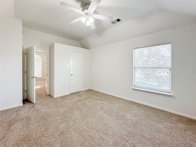 unfurnished bedroom featuring carpet floors, a closet, vaulted ceiling, and ceiling fan