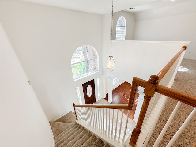 stairway featuring a notable chandelier, carpet floors, and a high ceiling