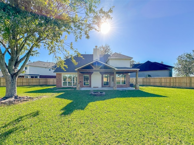 rear view of property with a lawn, a fire pit, and a patio