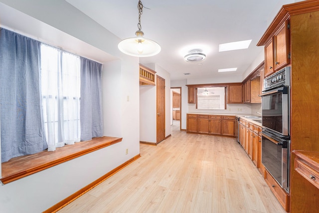 kitchen with pendant lighting, a skylight, light hardwood / wood-style flooring, and double oven