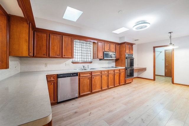 kitchen with sink, light hardwood / wood-style flooring, a skylight, decorative light fixtures, and stainless steel appliances