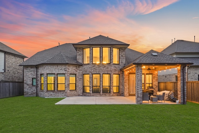 back house at dusk featuring outdoor lounge area, a yard, and a patio