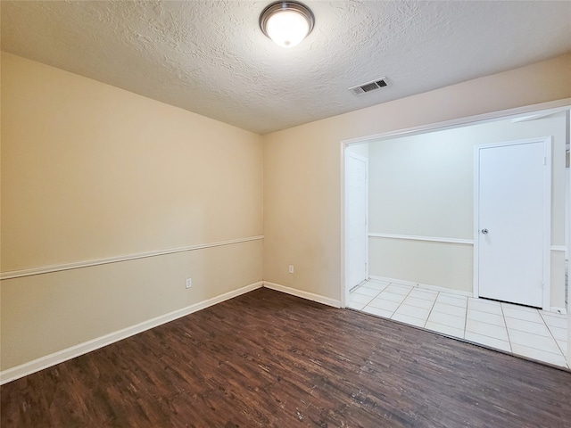 empty room with hardwood / wood-style floors and a textured ceiling