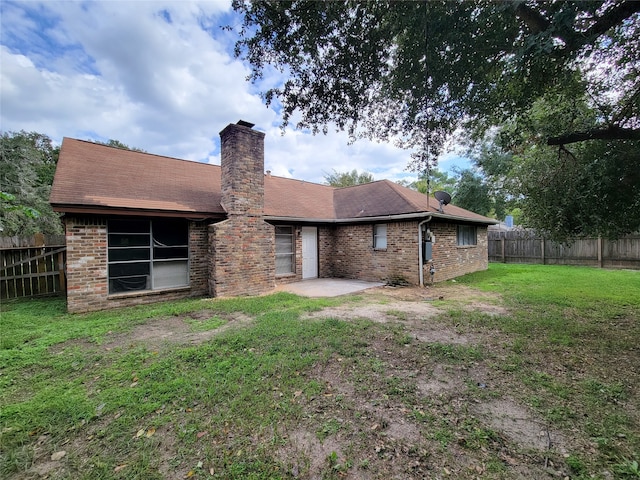 back of house featuring a lawn and a patio area