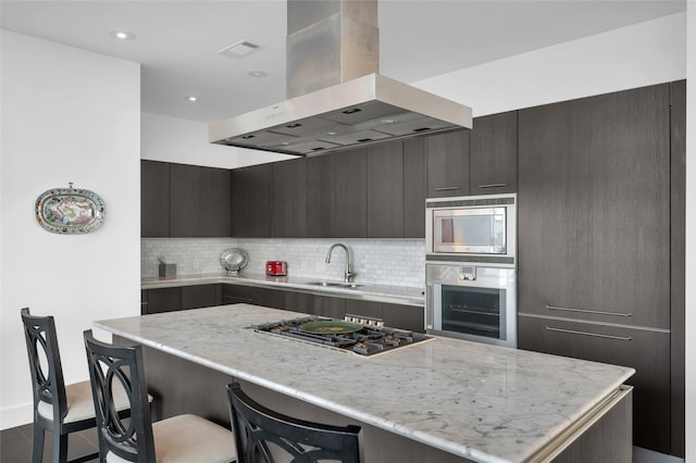 kitchen with decorative backsplash, stainless steel appliances, wall chimney exhaust hood, and sink