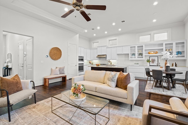 living room with crown molding, dark hardwood / wood-style flooring, ceiling fan, and sink