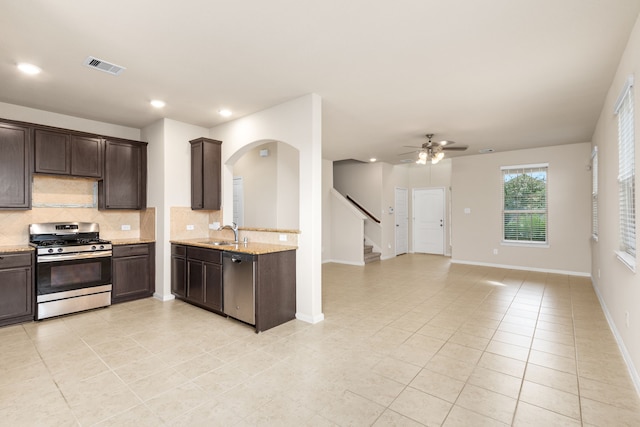 kitchen with tasteful backsplash, dark brown cabinetry, stainless steel appliances, ceiling fan, and sink